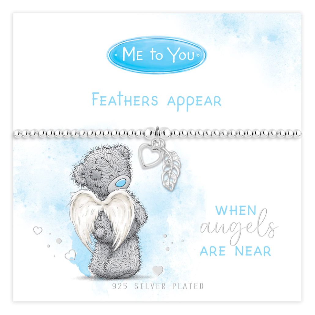A Me to You 'Feathers Appear' 925 sterling silver bracelet displayed on its white and light blue watercolor backing card. The bracelet features a silver chain with a silver heart charm, a silver feather charm, and a central silver bear charm with a blue teary eye and white angel wings.